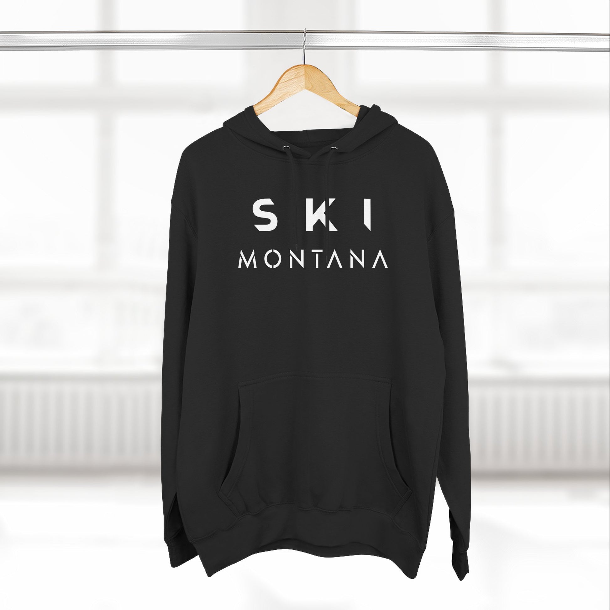 Black hoodie with 'SKI MONTANA' text on a hanger against a white background