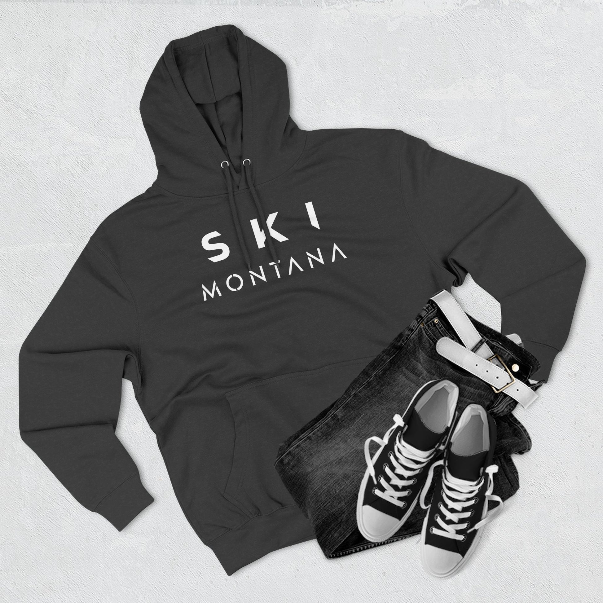 Dark gray hoodie with 'Ski Montana' text, black jeans, and black sneakers on a light gray background