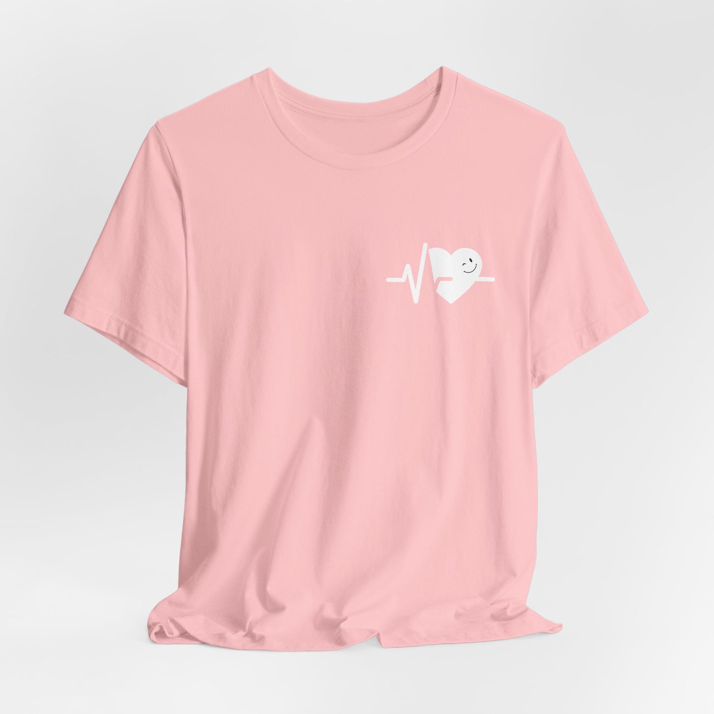 Pink t-shirt with a white heart smile face graphic on a light gray background